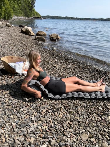 Woman relaxing on Adventure Mat on a pebble beach