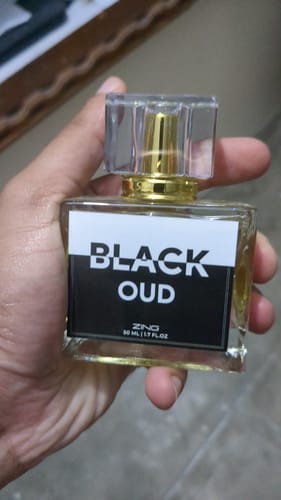Reviewer holding the square glass bottle of Black Oud perfume.