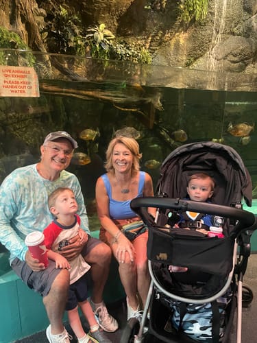 Reviewer smiling with her family while seated in front of a large aquarium tank.