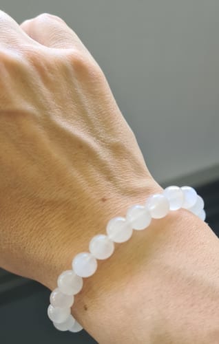 Client montrant le bracelet en pierre de lune véritable avec des perles translucides au poignet.