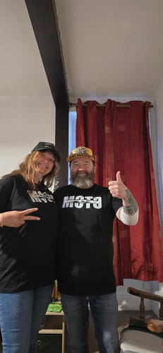Deux clients souriants portant le T-shirt noir COLLECTION PRISMA à l'intérieur.
