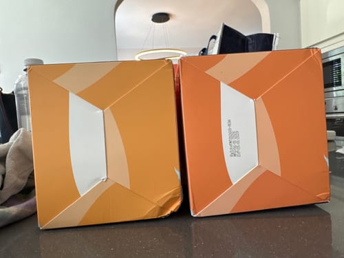 Customer showing two slightly different colored boxes for the RAndM Digital Box vape, one with a date printed and one without.