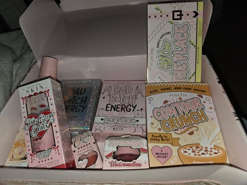 Reviewer's open box showing the Mystery Bad Bitch Energy Lip Duo packaging among other colorful makeup products.