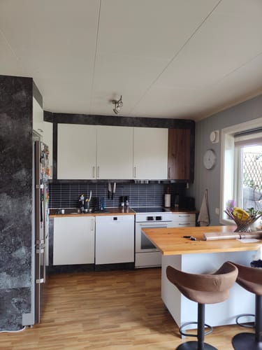 Anmelders kjøkken som viser de originale hvite skapene ved siden av ett skap dekket med Artisan Oak kontaktplast.