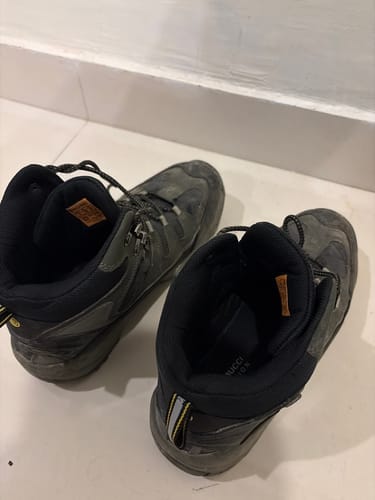 A customer's pair of dusty, dark EXPEDITION boots shown on a tile floor after their adventure.