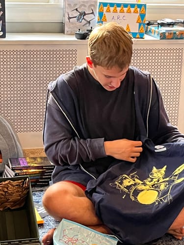 Customer looking at the navy Cat Drums T-Shirt with a yellow cat graphic.