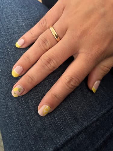 Kundin zeigt ihre fertige Maniküre mit den 'Lemon Sorbet' UV-Gelfolien, mit gelben Spitzen und Zitronenmotiven.