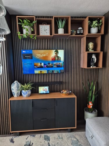 Customer's media wall featuring dark Premium Acoustic Slatted Wall Panels behind a TV and wooden box shelves.