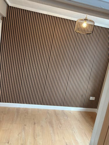 Customer's room showing a feature wall covered in the light-wood Premium Acoustic Slatted Wall Panels.