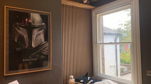 Reviewer's room showing the light wood acoustic slatted wall panel installed between a framed picture and a window.