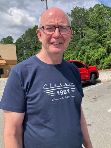 Reviewer smiling while wearing a navy blue Custom T-shirt with a 'Classic 1961' design.