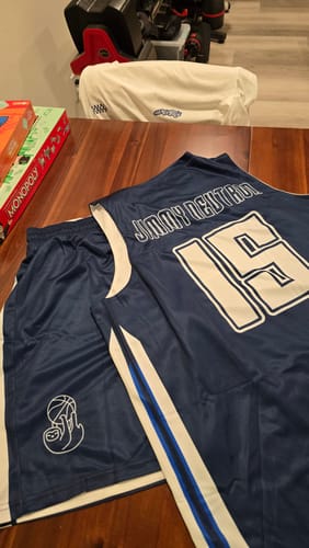 Customer's custom navy basketball jersey and shorts set laid out, showing the personalized name and number 15 on the back.
