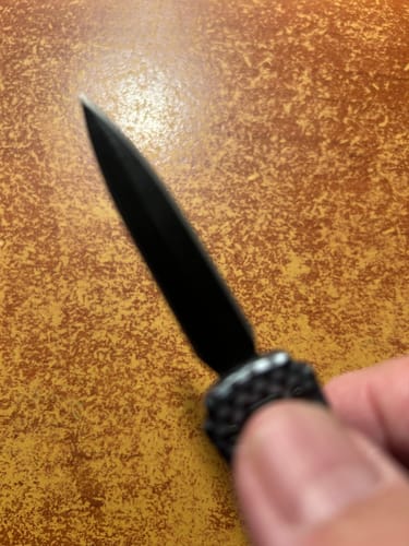 Close-up: A reviewer holding The Wasp Micro OTF, showing the sharp black blade against a textured surface.