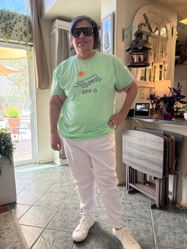 Reviewer standing indoors wearing the mint-colored SPF Zero t-shirt and white pants.