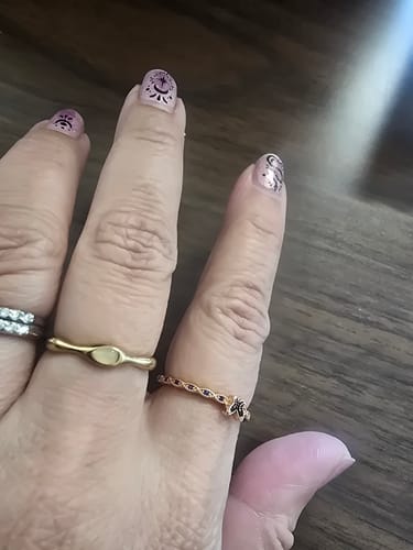 Reviewer's hand wearing the Amalfi Wave Gold Ring on the middle finger, next to two other rings.