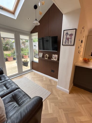 Customer's view of the premium acoustic slatted wall panel in a dark wood finish, installed as a TV feature wall.