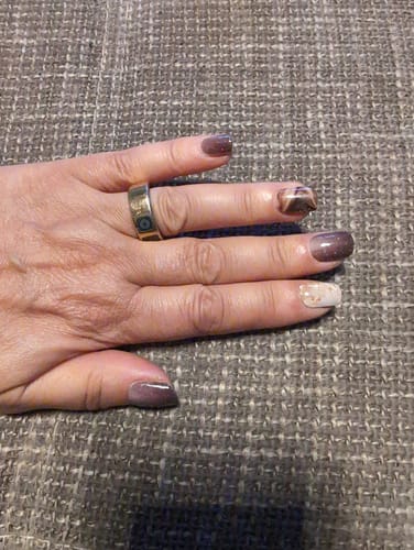 Hand einer Kundin, die die Crystal Merlot UV-Gel-Nagelfolien mit einem dunklen Ombré-Glitzer-Design zeigt.