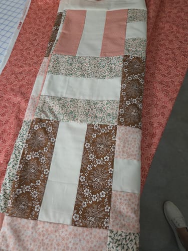 Customer's Picket Fences quilt top in progress, laid out on the chosen pink backing fabric.