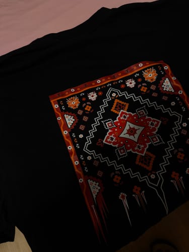 Customer's black Kover Oversized Shirt with a detailed, colorful rug-style graphic print laid flat.