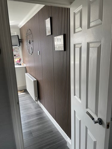 Customer's dark Premium Acoustic Slatted Wall Panels installed as a feature wall in a modern hallway.