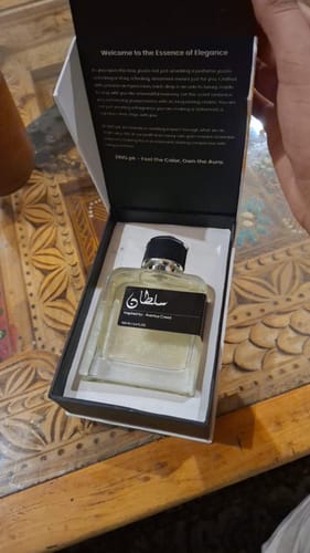 Customer holding open the elegant box containing a bottle from the OUD Supreme Bundle on a wooden table.