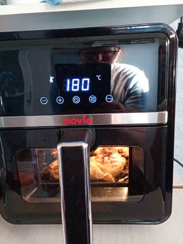 Recenzent gătind un pui întreg în friteuza Air Fryer Novio StonePro, setată la 180°C.