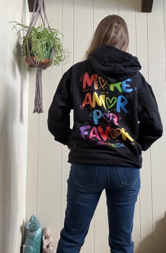 Reviewer from the back wearing the More Amor Vive Tu Vida Hoodie, showing the colorful graphic.