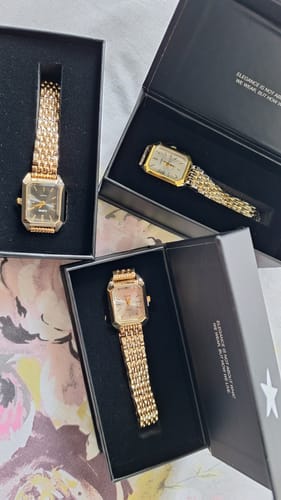 Customer's three gold-colored CLAIRE DE MAINS watches displayed in their open black gift boxes.