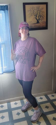 Reviewer wearing the purple Still Plays Outside T-shirt, showing its relaxed fit.