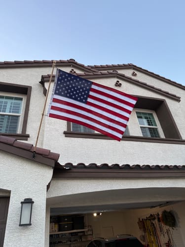 Reviewer's Ultra Heavy Duty American Flag mounted on the front of their house, waving gently.