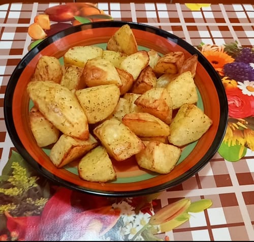 Client arătând un bol cu cartofi aurii, preparați la friteuza cu aer cald Novio StonePro.