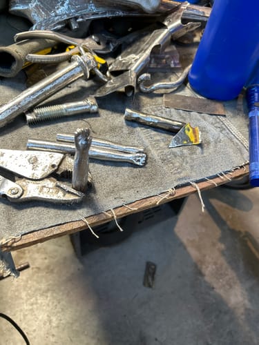 Customer's workbench with various metal pieces, including an intricate sculpted hand made using the cutting discs.