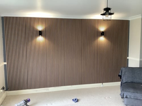 Customer's completed feature wall using the light wood Premium Acoustic Slatted Wall Panels with two wall lights.