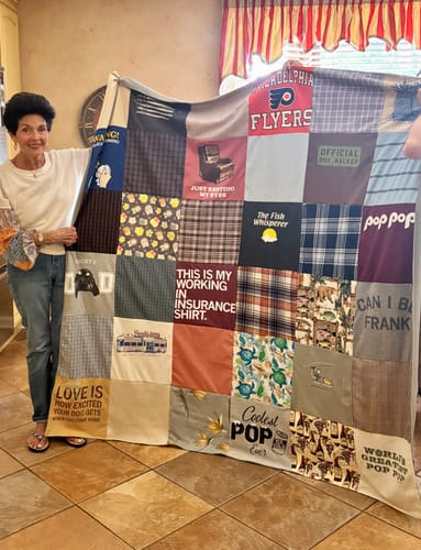 Reviewer holding a large Project Repat T-Shirt Quilt made from memorable family t-shirts.