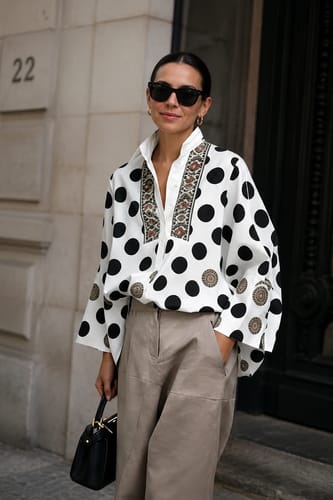 Reviewer wearing the loose Polka Dot Printed V-Neck Blouse with long sleeves, tucked into casual trousers.