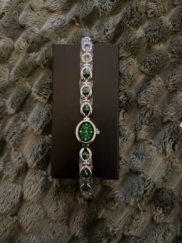 Customer's PERLE DE MAINS watch with a green dial and stone-accented band, displayed on its product box.