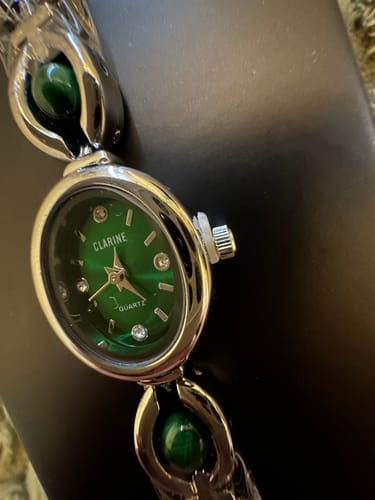 Close-up of the reviewer's PERLE DE MAINS watch, showing the detailed emerald green dial and silver band.