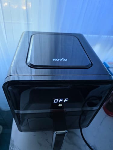 Client arătând o vedere de sus a friteuzei Air Fryer Novio StonePro. Produsul este oprit, cu panoul superior vizibil.