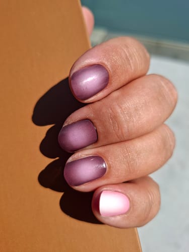 Rezensentin mit einer Maniküre, die pflaumenfarbene Plum Nova Aurora Folien und einen andersfarbigen Nagel kombiniert.
