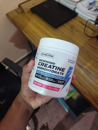 Customer holding a white tub of Wellcore Micronised Creatine Monohydrate in the Fruit Fusion flavor.