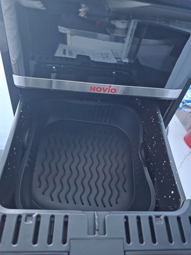 Client arătând sertarul friteuzei Novio StonePro, cu cuva acoperită cu o tavă de silicon neagră.