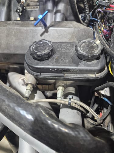Reviewer's stock Mopar master reservoir with original plastic caps before installing the TBM billet caps.