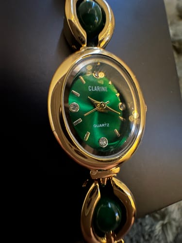 Close-up: Reviewer's PERLE DE MAINS watch, showing the vibrant green dial and polished gold case.