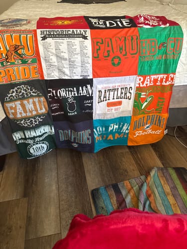 Customer's Project Repat T-Shirt Quilt draped over a bed, featuring various colorful college and team shirts.