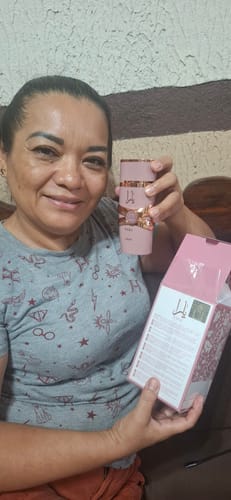 Una clienta sonríe mientras sostiene el perfume Lattafa Yara Elixir y su caja rosa abierta.