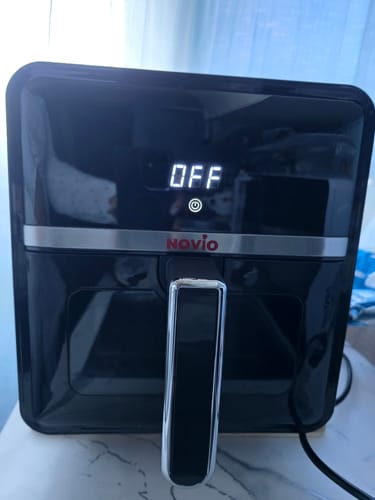 Client arătând friteuza Air Fryer Novio StonePro neagră. Ecranul digital frontal indică 'OFF'.