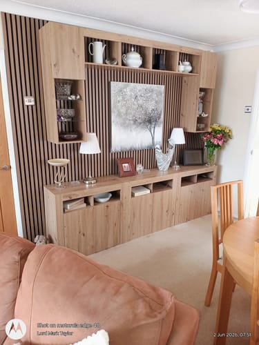 Customer's living room featuring the dark acoustic slatted wall panels behind a light wood entertainment unit.