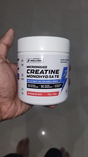 Customer holding a white tub of Wellcore's Watermelon Wave Creatine Monohydrate.