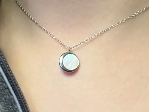 Close-up of a customer wearing the silver Moonlight Mother of Pearl Pendant, highlighting its luminous center.