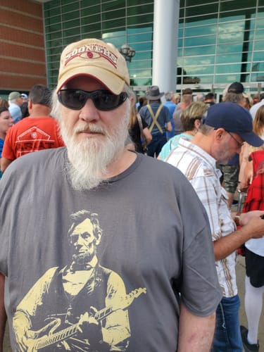 Customer wearing a grey t-shirt with a graphic of Abraham Lincoln playing a guitar.